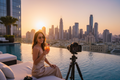 Luxury travel influencer at a 5-star hotel rooftop pool with city skyline at golden hour